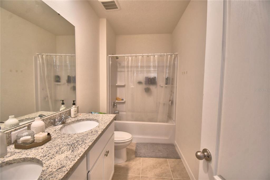 2839 Moulin Road Davenport, FL 33837 - Photo 50 of 75 a bathroom with a granite countertop sink a toilet and shower