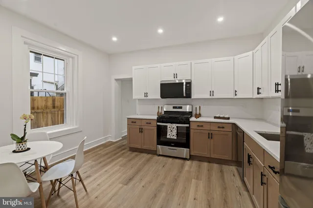 a kitchen with stainless steel appliances a stove a sink dishwasher a microwave oven with a dining table and chairs