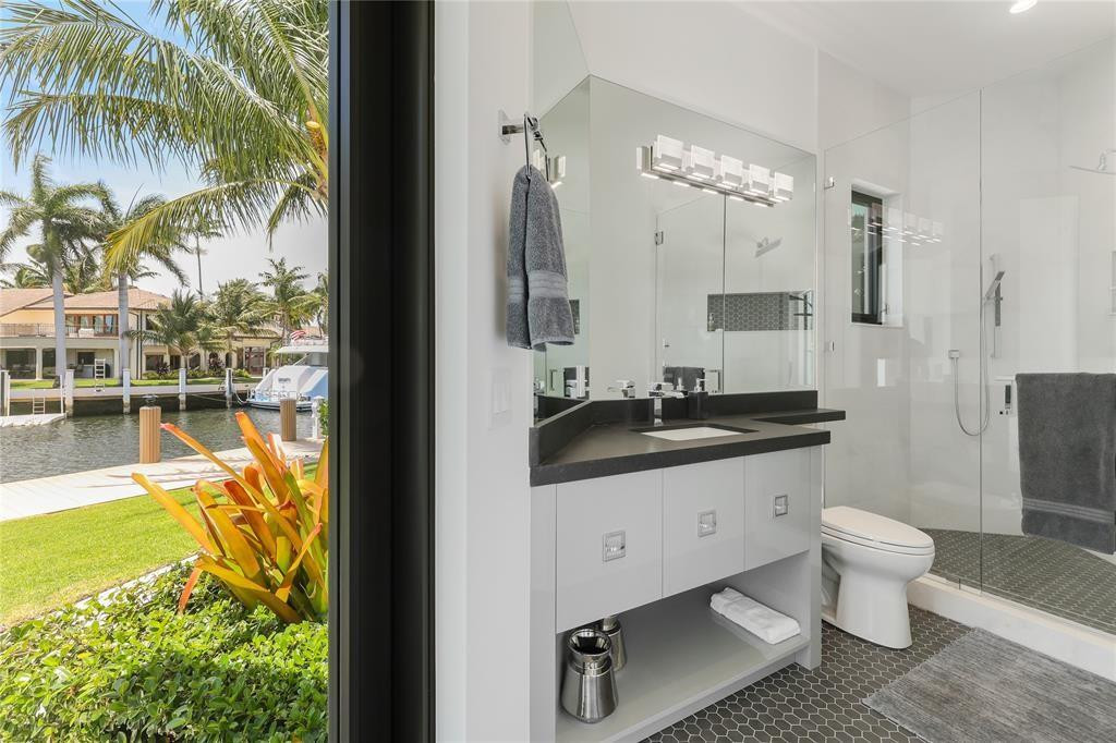 2550 Northeast 31st Court Lighthouse Point, FL 33064 - Photo 55 of 84 a bathroom with a granite countertop sink a toilet a mirror and shower