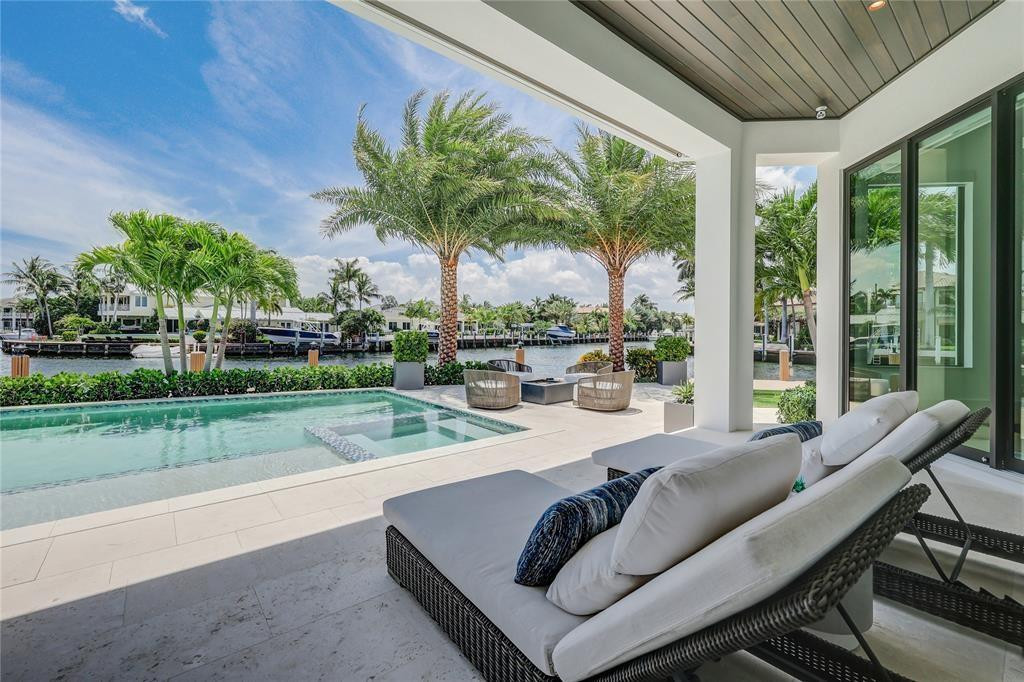 2550 Northeast 31st Court Lighthouse Point, FL 33064 - Photo 71 of 84 a view of a patio with couches dining table and chairs under an umbrella with a big yard
