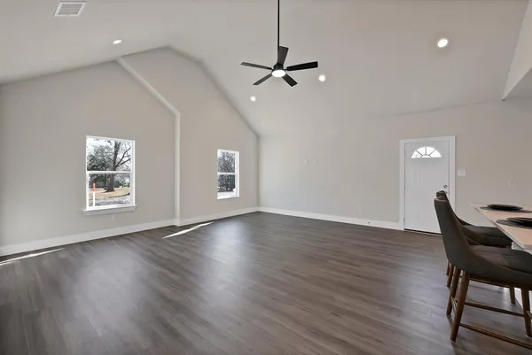 a view of a room with wooden floor a ceiling fan and windows
