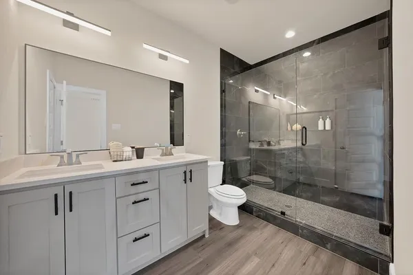 a bathroom with a double vanity sink toilet a mirror and shower
