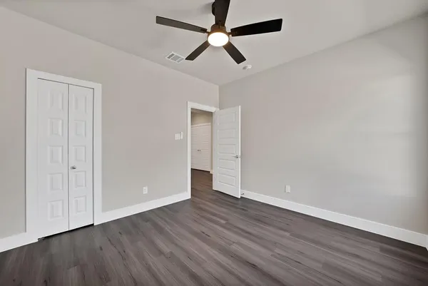 an empty room with wooden floor ceiling fan and window