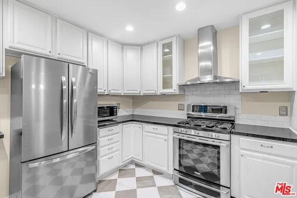 a kitchen with stainless steel appliances granite countertop a stove and a white cabinets