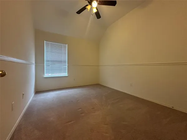 an empty room with a chandelier fan and windows