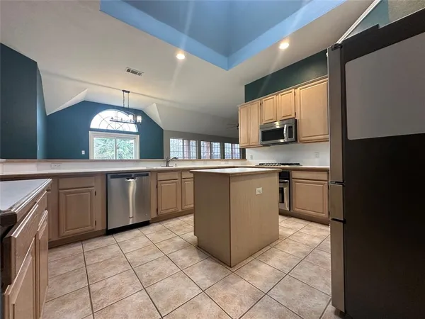 a kitchen with stainless steel appliances a sink a stove a microwave a sink a refrigerator and cabinets