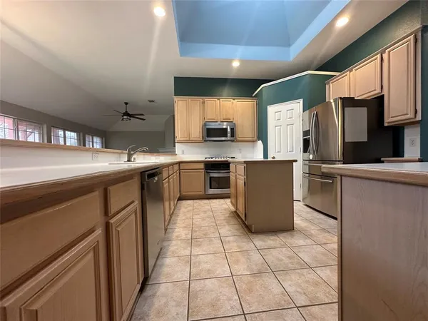 a kitchen with a sink a counter top space stainless steel appliances and cabinets