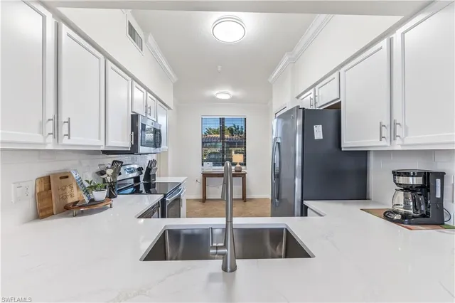 a kitchen with stainless steel appliances granite countertop a sink refrigerator and cabinets