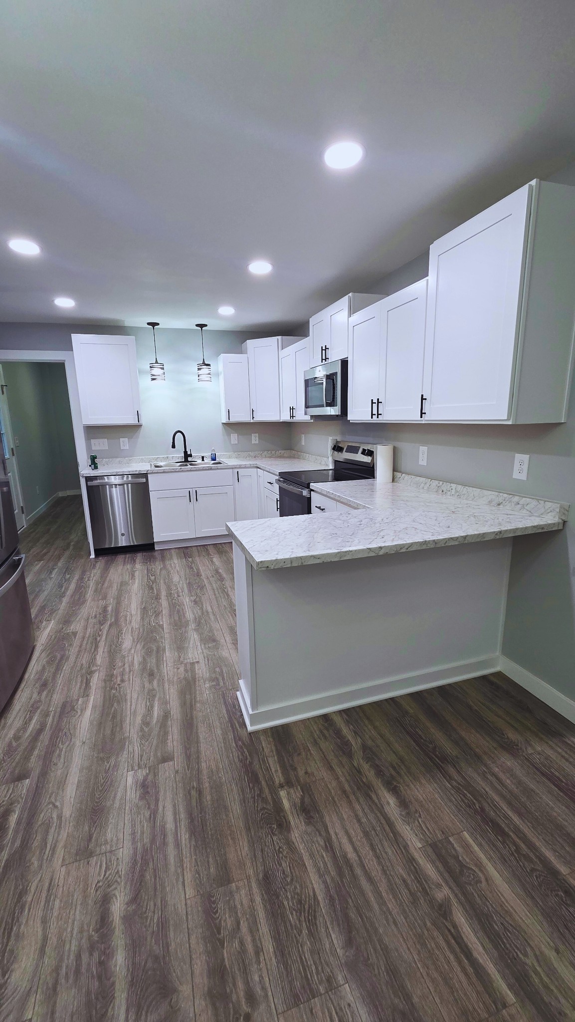 1080 Veterans Road Ashland City, TN 37015 - Photo 17 of 35 a large white kitchen with kitchen island a sink dishwasher a stove and a refrigerator with wooden floor