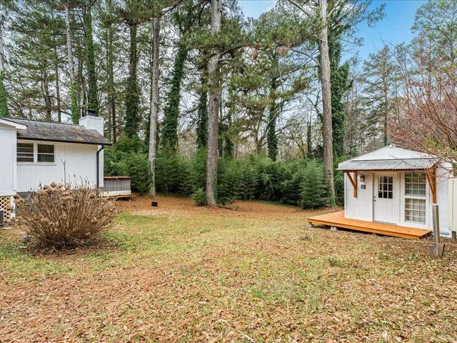 a front view of a house with a dirt yard and a large tree