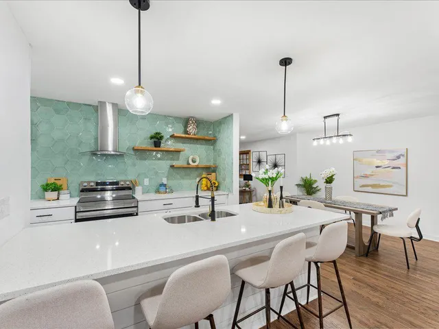 a kitchen with stainless steel appliances a kitchen island a stove a table and chairs with wooden floor