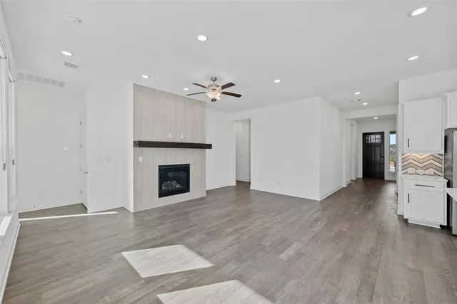 a view of a livingroom with a fireplace a ceiling fan and kitchen view