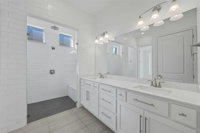 a spacious bathroom with double sink a mirror a light fixtures and