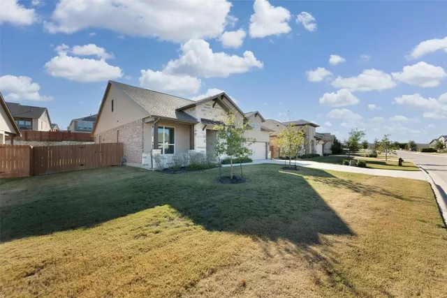a view of a house with a big yard plants and large trees