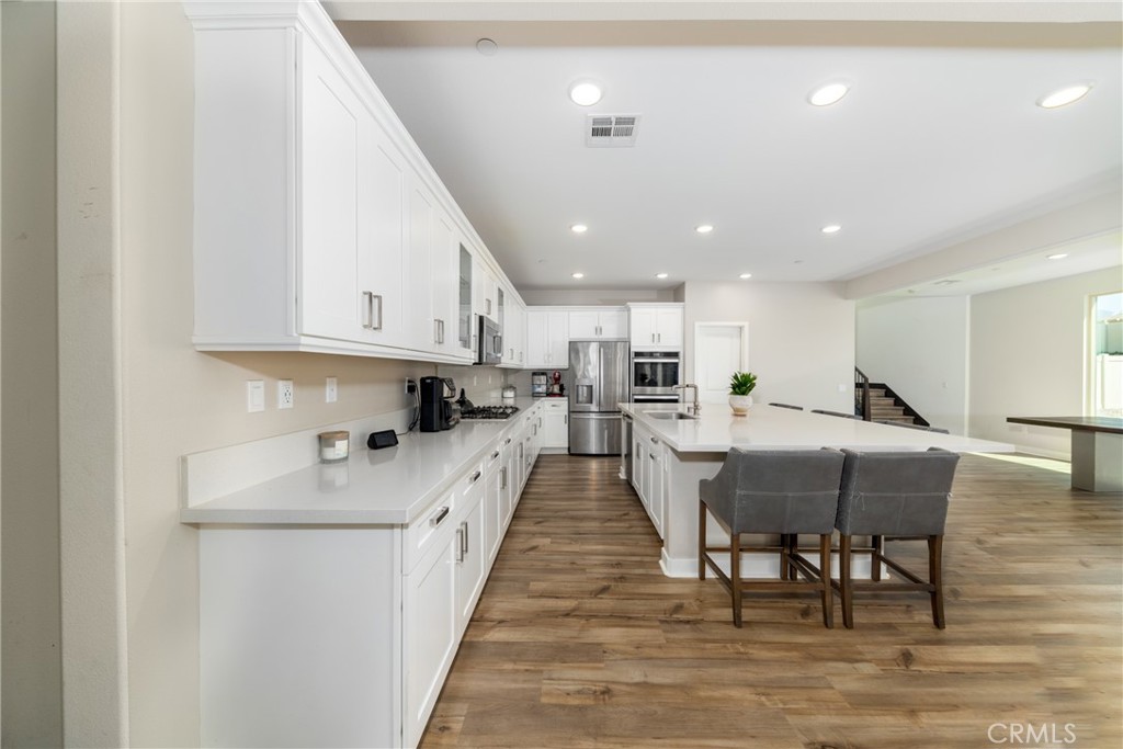 1740 Boysen Way Beaumont, CA 92223 - Photo 15 of 49 a large white kitchen with lots of counter space wooden floor dining table and chairs