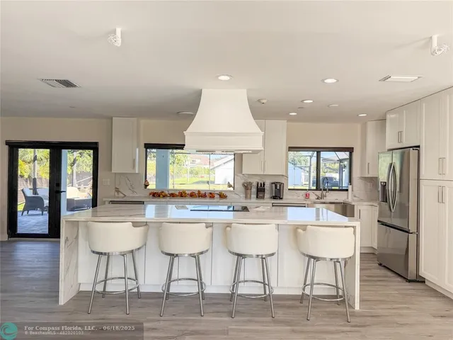 a kitchen with stainless steel appliances a dining table chairs and wooden floor