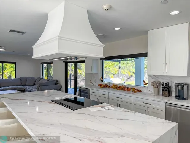 a kitchen with kitchen island granite countertop a sink a counter top space and stainless steel appliances