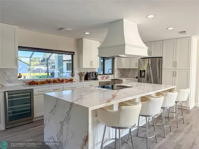 a kitchen with stainless steel appliances granite countertop a table chairs sink and wooden cabinets