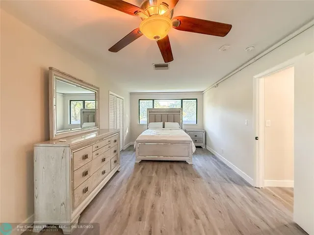 a spacious bedroom with a bed and wooden floor