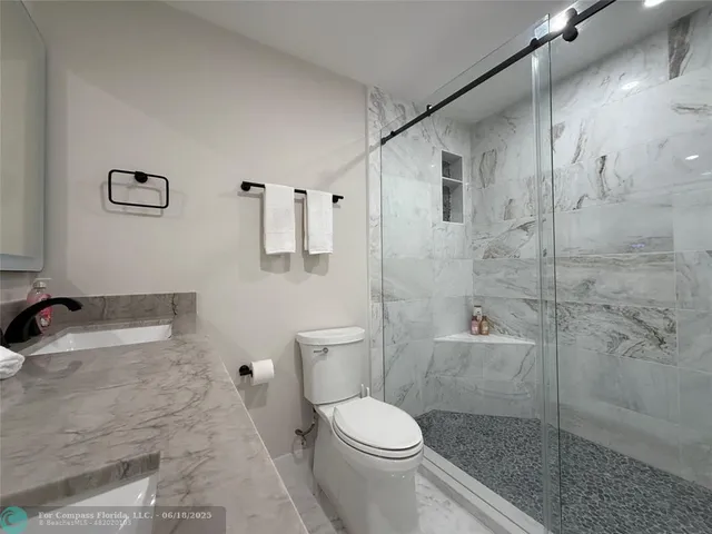 a bathroom with a granite countertop bathtub shower sink mirror and toilet