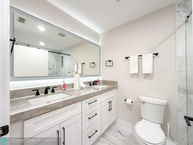 a bathroom with a toilet sink double vanity and mirror