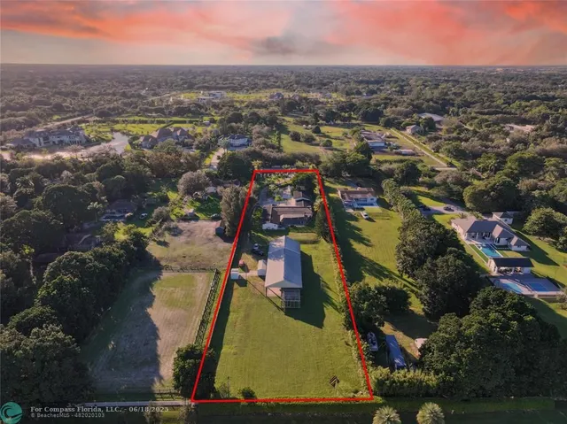 an aerial view of residential houses with outdoor space and trees