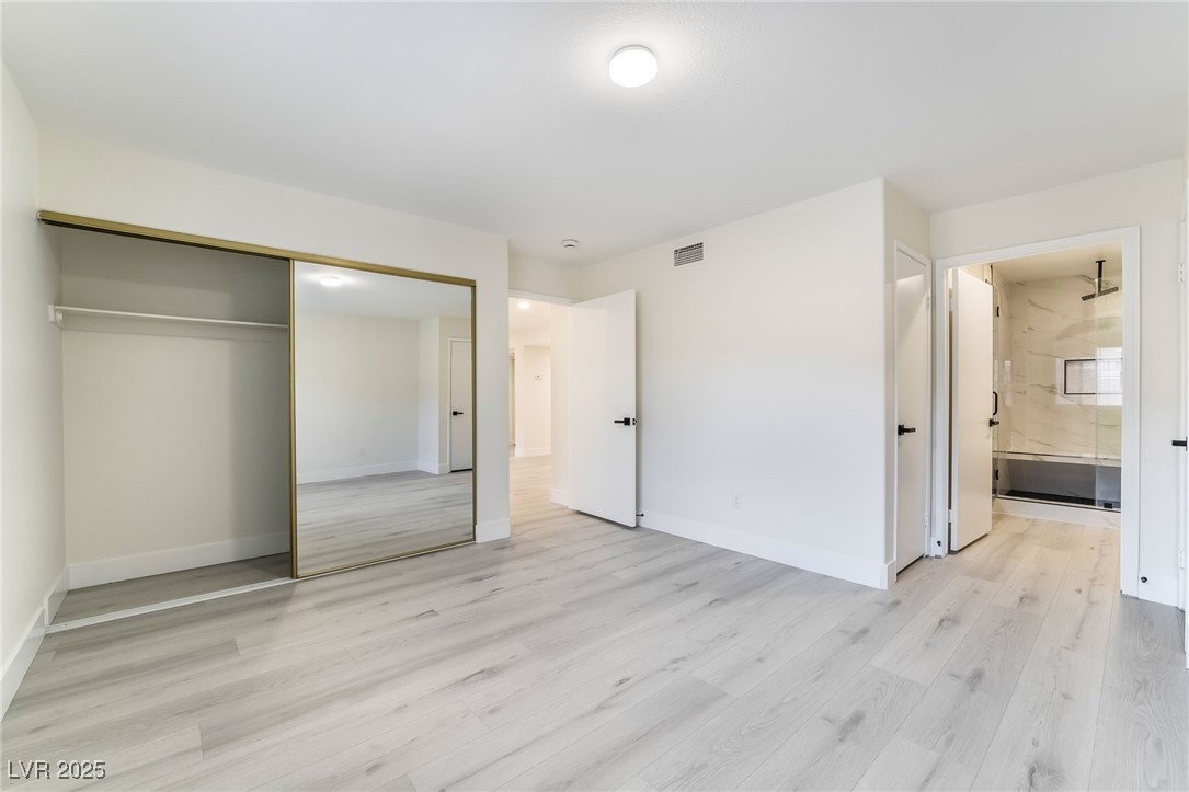 9070 Spring Mountain Road, Unit 119 Las Vegas, NV 89117 - Photo 24 of 39 Unfurnished bedroom featuring baseboards, visible vents, ensuite bath, light wood-style floors, and a closet