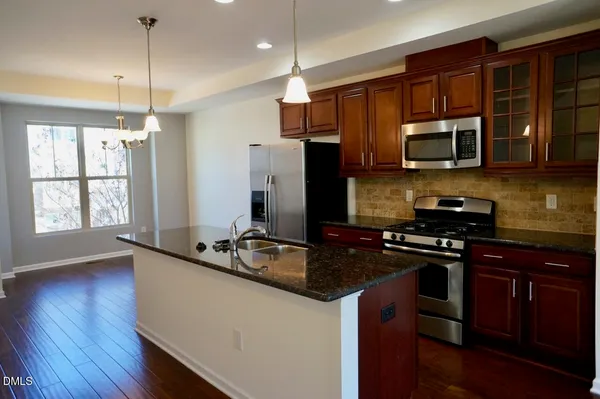 a kitchen with stainless steel appliances granite countertop a stove a sink dishwasher a refrigerator and a microwave oven with wooden floor