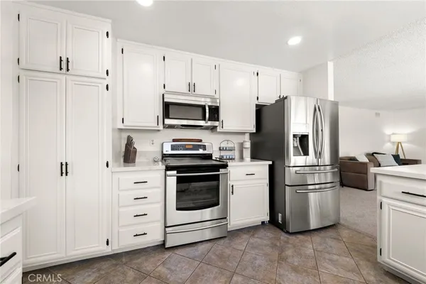 a kitchen with stainless steel appliances kitchen island granite countertop a refrigerator and a dining table