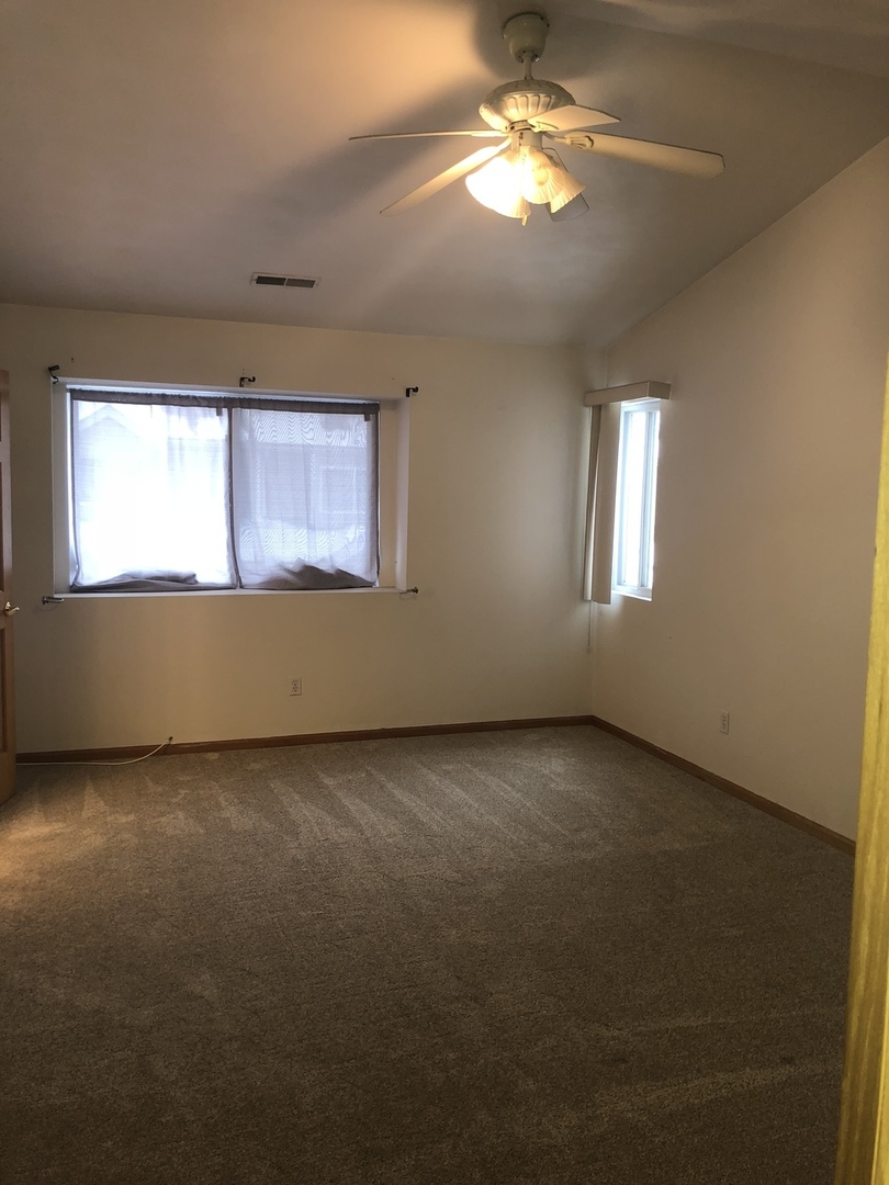 6032 Park Ridge Road, Unit 6032 Loves Park, IL 61111 - Photo 10 of 13 an empty room with windows and ceiling fan