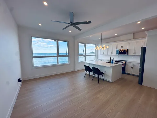 a living room with stainless steel appliances kitchen island granite countertop furniture and a large window