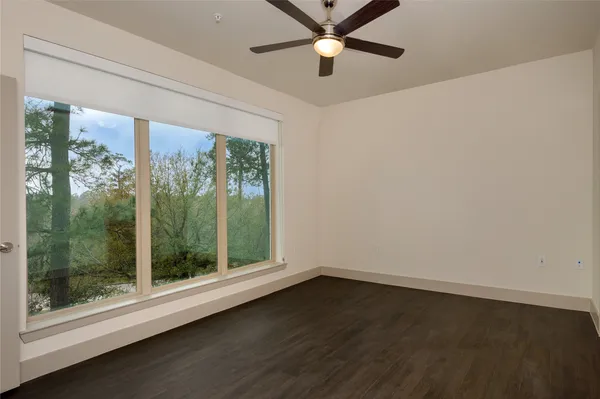 a view of a room with a large window ceiling fan and wooden floor