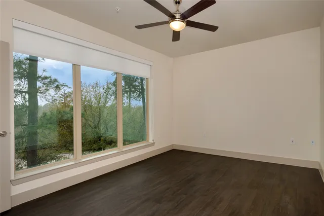 a view of a room with a large window ceiling fan and wooden floor