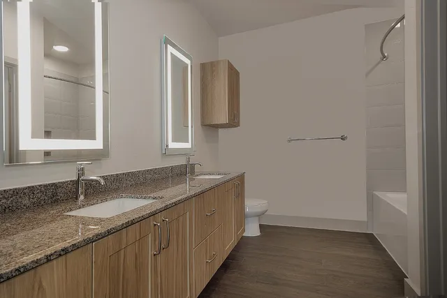 a bathroom with a granite countertop sink a mirror and a toilet