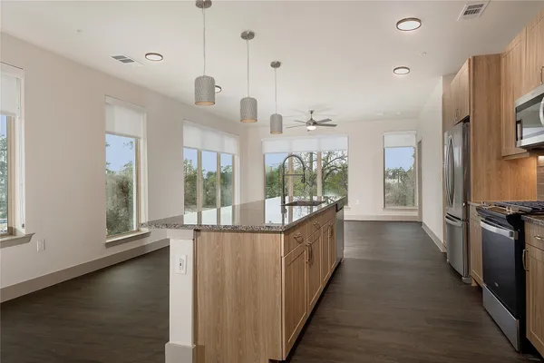 a view of a kitchen and an empty room with wooden floor and windows