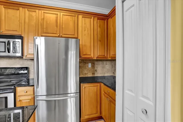 a kitchen with stainless steel appliances granite countertop a refrigerator and a stove top oven
