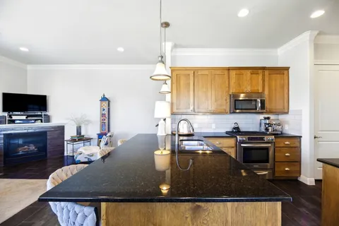 a kitchen with kitchen island a stove a sink a microwave a dining table and chairs