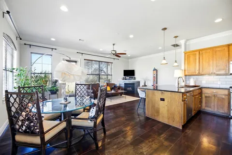 a kitchen with stainless steel appliances kitchen island granite countertop a table chairs sink and cabinets