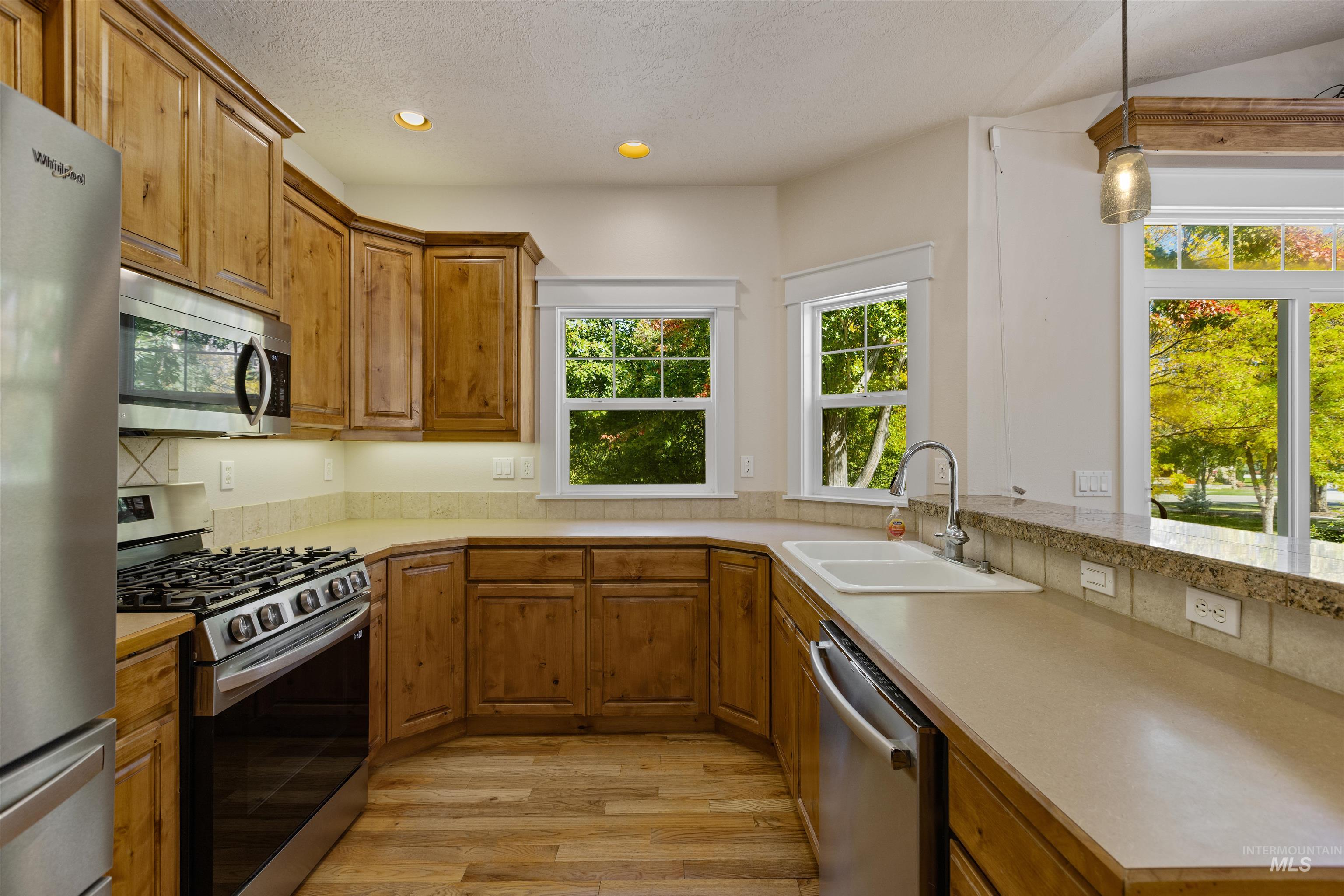 5426 West School Ridge Road Boise, ID 83714 - Photo 24 of 39 U-shaped kitchen with wood cabinetry, stainless steel appliances, and a double basin sink