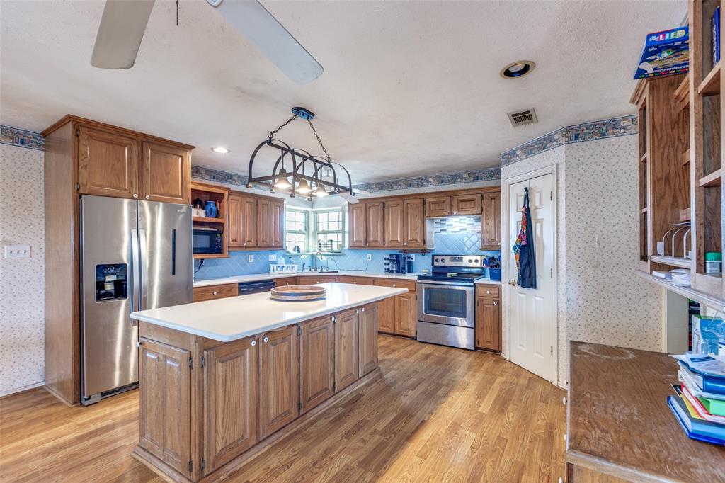 453 County Road 371 Anna, TX 75409 - Photo 11 of 26 a kitchen with stainless steel appliances granite countertop a refrigerator a sink dishwasher a stove and a dining table with wooden floor