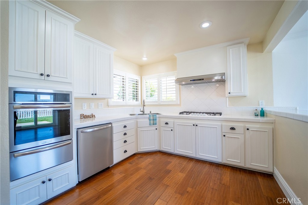 25276 Barque Way Dana Point, CA 92629 - Photo 22 of 61 a kitchen with granite countertop white cabinets and white appliances