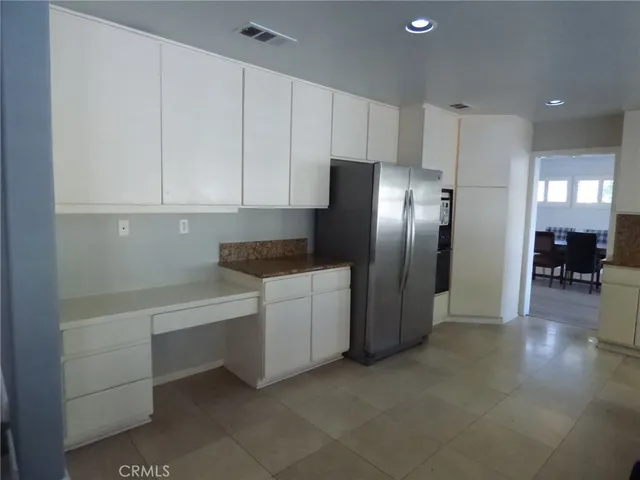 a kitchen with stainless steel appliances a refrigerator and white cabinets