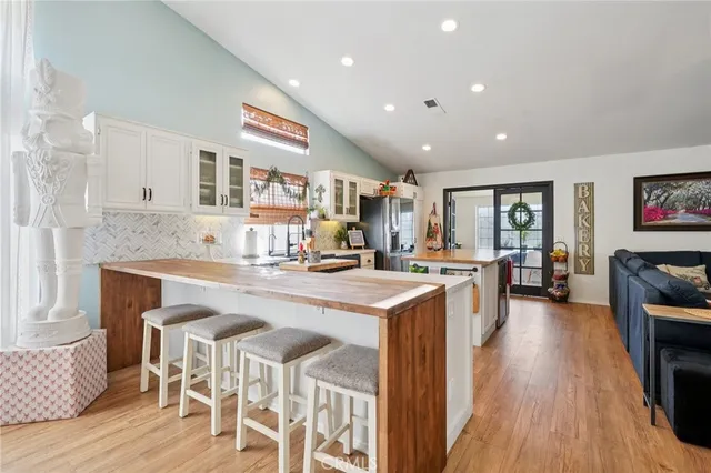 a open kitchen with stainless steel appliances granite countertop a stove top oven a sink dishwasher and a dining table with wooden floor