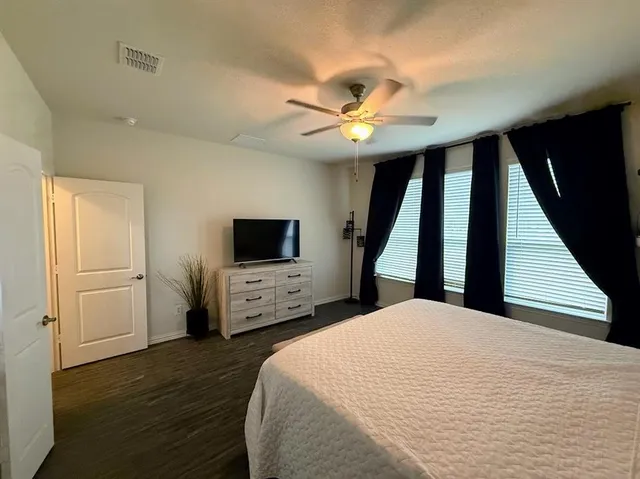 a bedroom with a large bed a flat tv screen and dresser