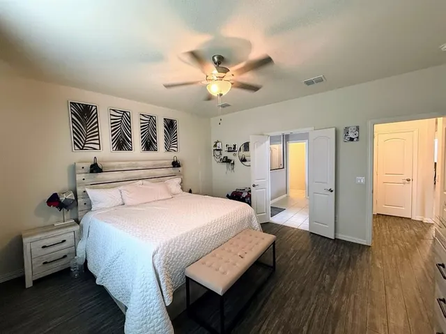 a spacious bedroom with a bed and wooden floor