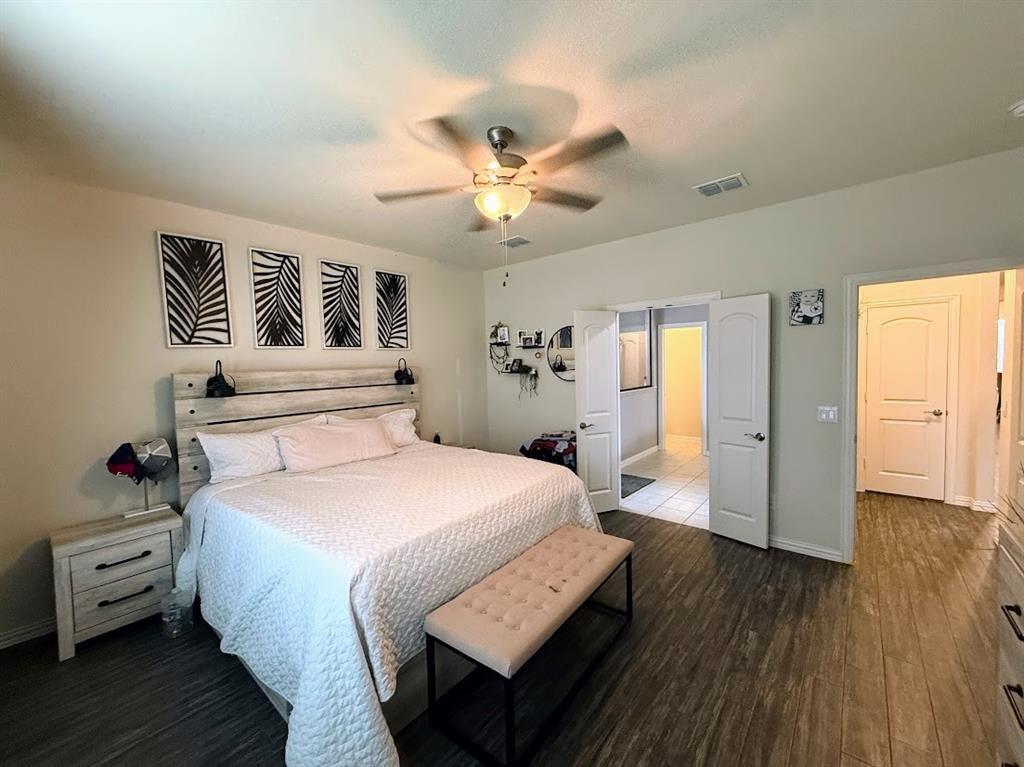1109 Pinnacle Ridge Road Fort Worth, TX 76052 - Photo 19 of 40 a spacious bedroom with a bed and wooden floor