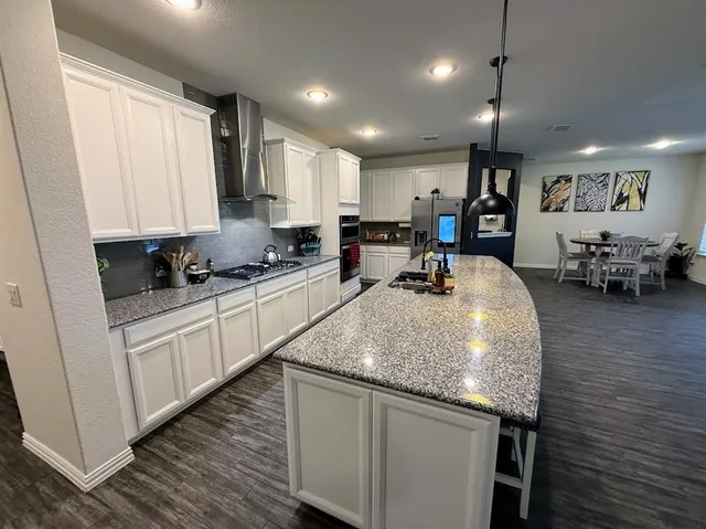 a kitchen with stainless steel appliances granite countertop a sink refrigerator and cabinets