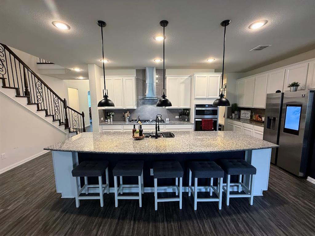 1109 Pinnacle Ridge Road Fort Worth, TX 76052 - Photo 6 of 40 a kitchen with stainless steel appliances kitchen island a dining table chairs and wooden floor
