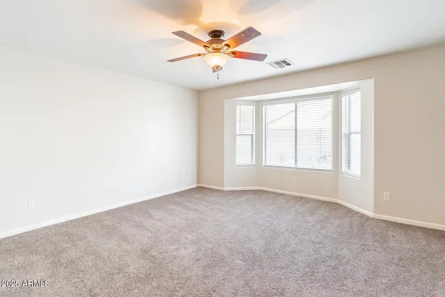 an empty room with ceiling fan and window