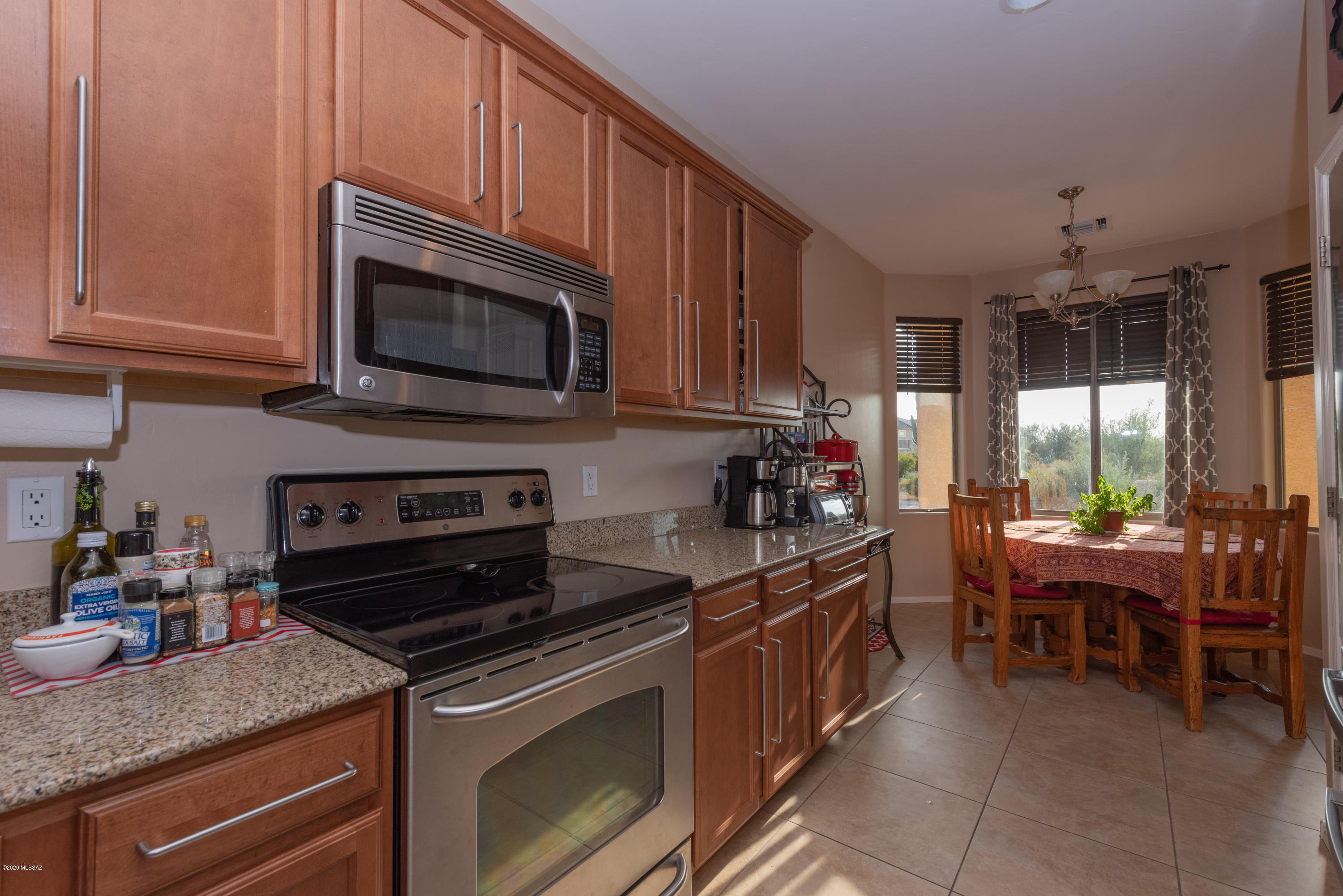 12910 Bloomington Loop Oro Valley, AZ 85755 - Photo 8 of 30 a kitchen with granite countertop a stove top oven microwave and cabinets
